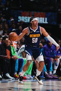 a basketball player dribbling the ball during a game in front of an audience