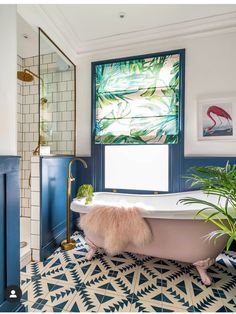 a bathroom with blue and white tile flooring and a pink bathtub next to a window