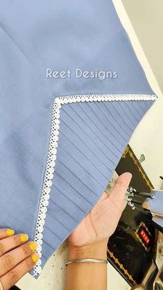 a woman using scissors to cut fabric on a piece of blue cloth with white trim