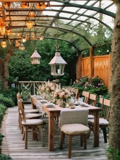 an outdoor dining area with wooden tables and chairs, lanterns hanging from the ceiling and flowers in vases on the table