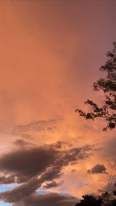 the sky is filled with clouds as the sun goes down in the distance behind some trees