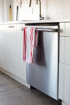 a dishwasher with a towel hanging from it's pull - out rack