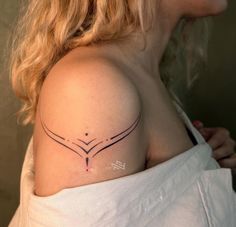 a woman with a tattoo on her shoulder that has two lines in the shape of an arrow