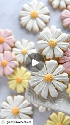 cookies decorated with white and yellow flowers are on a plate next to other small ones