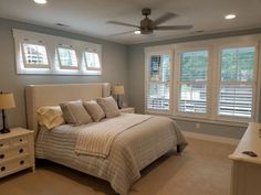 a bedroom with a bed, dresser and two windows in it's center area