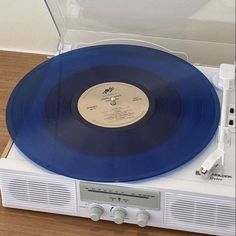 a blue record player sitting on top of a white radio case with its lid open