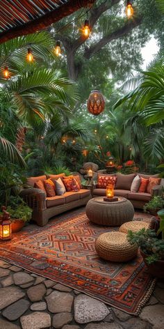 an outdoor living area with lots of plants and lights hanging from the ceiling above it