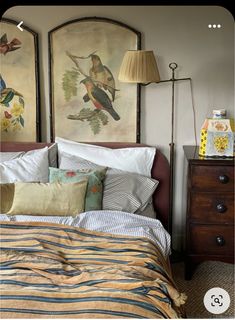 a bed room with a neatly made bed and two paintings on the wall