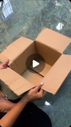 a woman holding a cardboard box with a hole in the middle on top of it