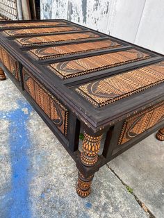 an old coffee table with intricate designs on the top and bottom, sitting in front of a building