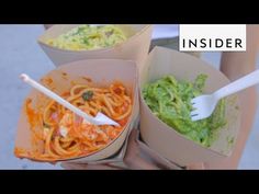 three takeout boxes filled with pasta and guacamole, one has a fork in it