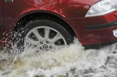 a red car driving through some water with it's front wheel in the air