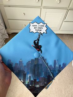 someone is holding up a graduation cap that has a man on a tightrope