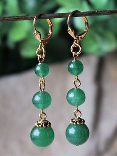 "This simple yet elegant pair of earrings features three emerald green jade gemstones. Hanging from a surgical steel lever-back, it measures 2.5\" in length. Earrings are light weight and sway gracefully as you move about your day. These beautiful dangle earrings are unique, feminine and eye-catching, a great accent to any wardrobe. Also available in sterling silver plate. Available with sculpted clip-on earrings top, please see last photo." Elegant Green Round Clip-on Earrings, Elegant Green Nickel-free Clip-on Earrings, Dangle Jade Earrings With Matching Set, Jade Dangle Earrings Jewelry Set, Jade Dangle Earrings With Matching Set, Green Gemstone Round Bead Earrings, Luxury Dangle Jade Earrings With Matching Set, Green Gemstone Earrings With Round Beads, Elegant Nickel-free Green Jewelry