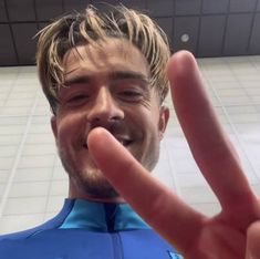 a man making the peace sign with his hand in front of him and wearing a wet suit