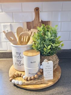 a wooden tray holding utensils, spoons and a potted plant