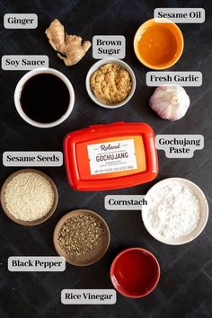 an assortment of spices and condiments on a black surface with labels describing them