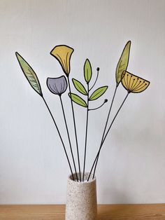 a vase filled with flowers on top of a wooden table next to a white wall