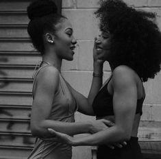 two women standing next to each other in front of a building