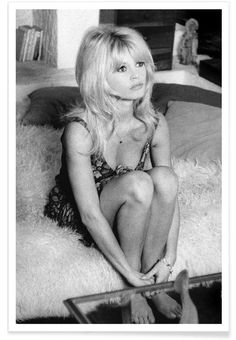 a black and white photo of a woman sitting on a bed with her legs crossed