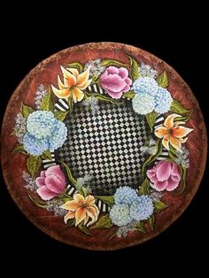 an artistically painted plate with flowers and leaves in the center on a black background