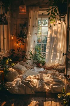 an unmade bed sitting in front of a window with plants on the windowsill