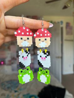 a pair of earrings made out of legos is being held up by someone's hand