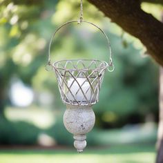 a white candle holder hanging from a tree