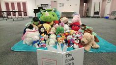 stuffed animals are sitting in the middle of an open book on top of a blue rug