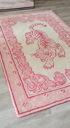 a pink and white rug with a tiger design on the center in front of a mirror