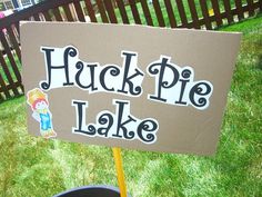 a sign that says huckle pie lake in front of a potted plant on the grass