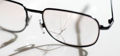 a broken pair of glasses sitting on top of a white table next to a shadow