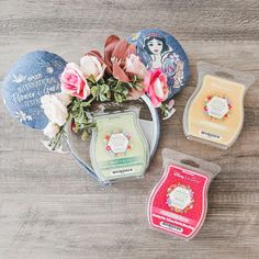 three different types of soaps on a wooden surface with flowers in the middle and two small ones sitting next to each other