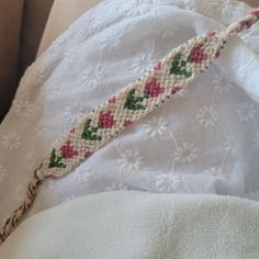 a close up of a piece of cloth with flowers on it and a beaded cord