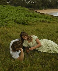 two people are laying in the grass and smiling at each other while one person is holding his head