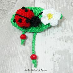 a crocheted ladybug brooch with white and red flowers on it