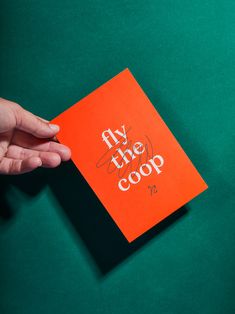 a person holding an orange book with the words my the coop on it