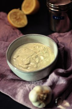 a bowl filled with soup next to some sliced lemons and garlic on a purple towel