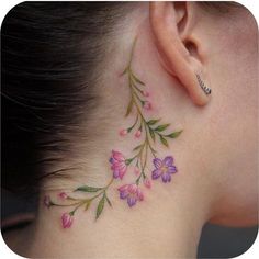 a woman's behind the ear tattoo with pink and purple flowers on her neck