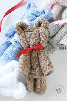 several knitted teddy bears are lined up on a white surface and tied with red ribbon