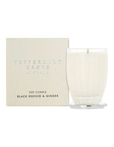 a white candle in front of a box on a white background with the words black orchid and ginger