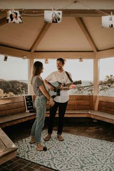 a man and woman playing guitar in a tent