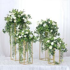 four gold plant stands with white flowers and greenery