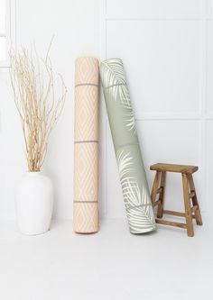 two yoga mats and a stool in front of a white wall with palm leaves on it