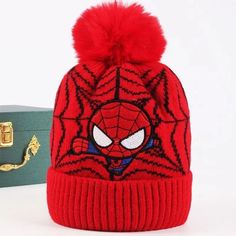 a red spiderman hat next to a suitcase