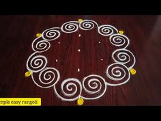 a circular design made with white and yellow flowers on a wooden table top, in the shape of a circle