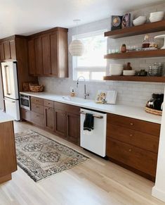 a kitchen with wooden cabinets, white appliances and an area rug in front of the sink