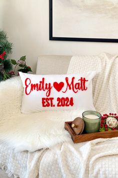 a white couch with a christmas pillow and candle on it