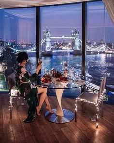 a woman sitting at a table in front of a large window overlooking the city skyline