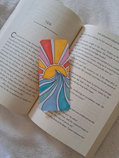 an open book with a colorful piece of paper on it's cover next to a white blanket